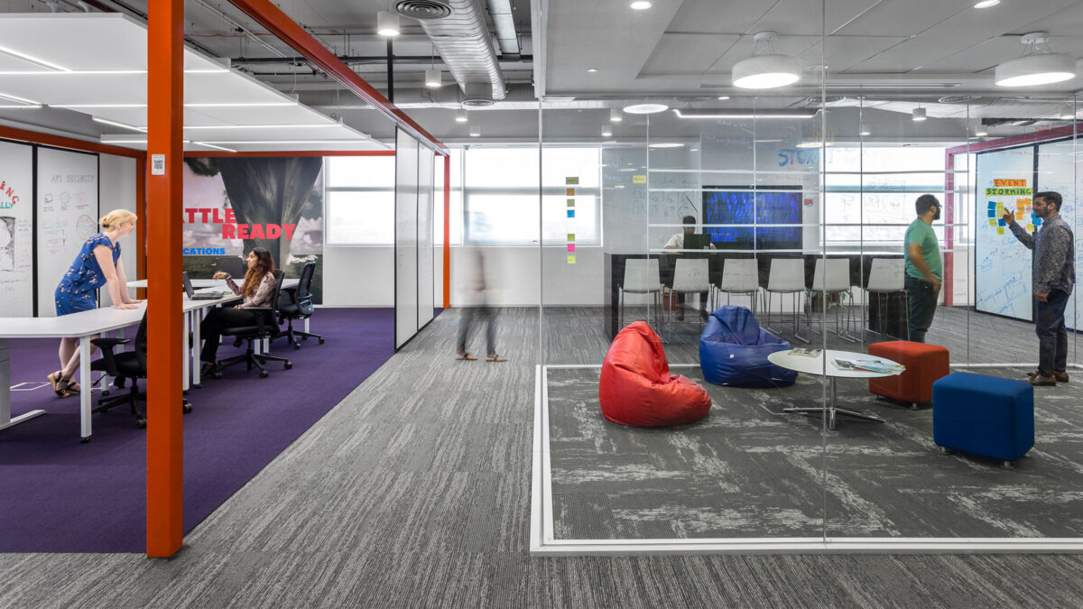 people collaborating in breakout area with man giving presentation and person at table