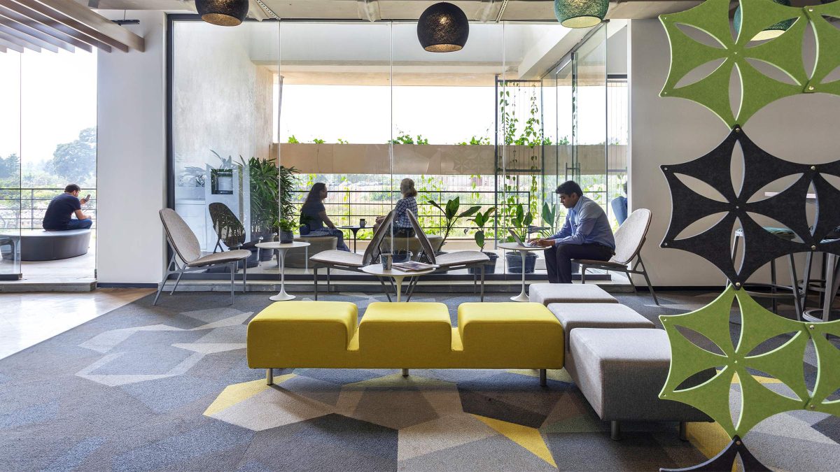 man working, man in room and women talking in casual area