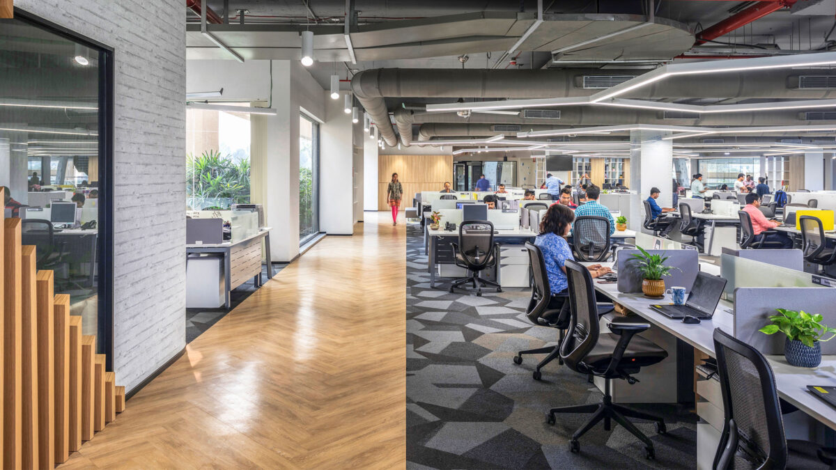 people working at desks and woman walking down corridor