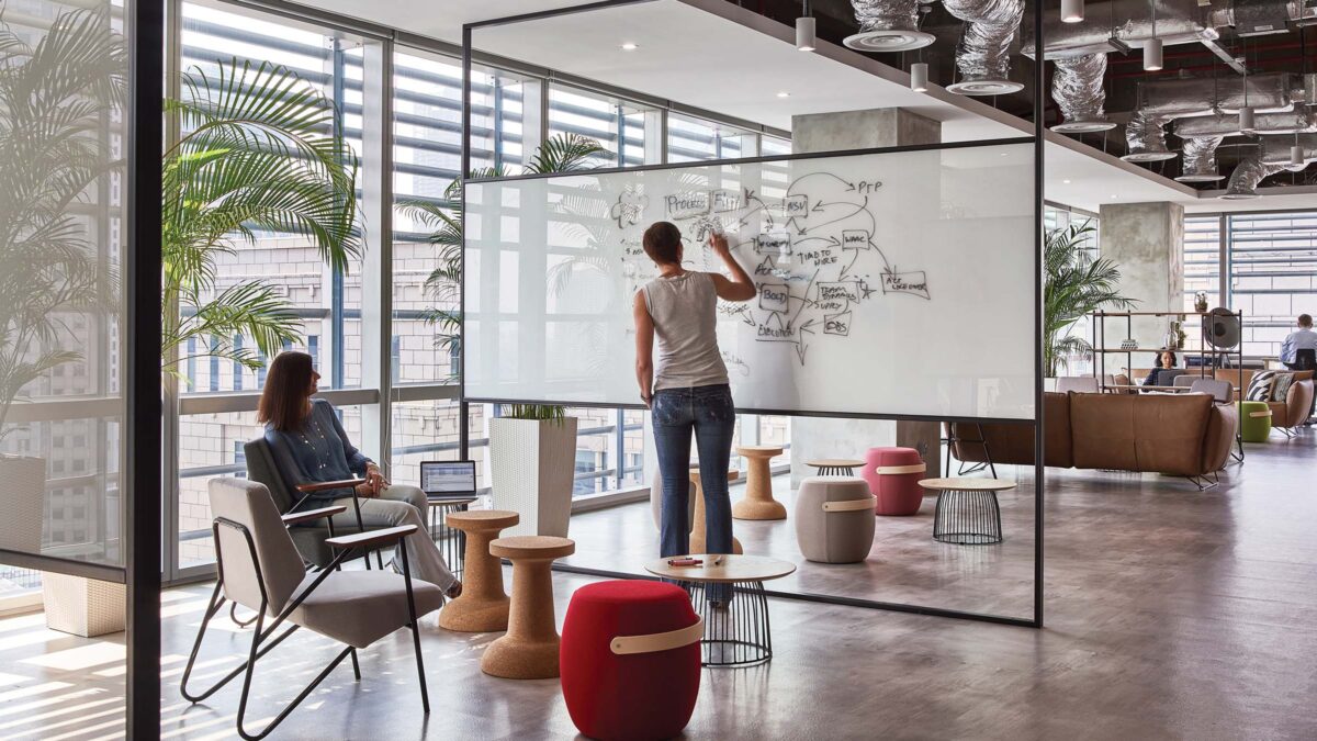 Women collaborating and woman writing on whiteboard