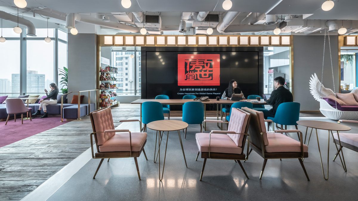 People collaborating at tables in front of av wall and view of lounge area