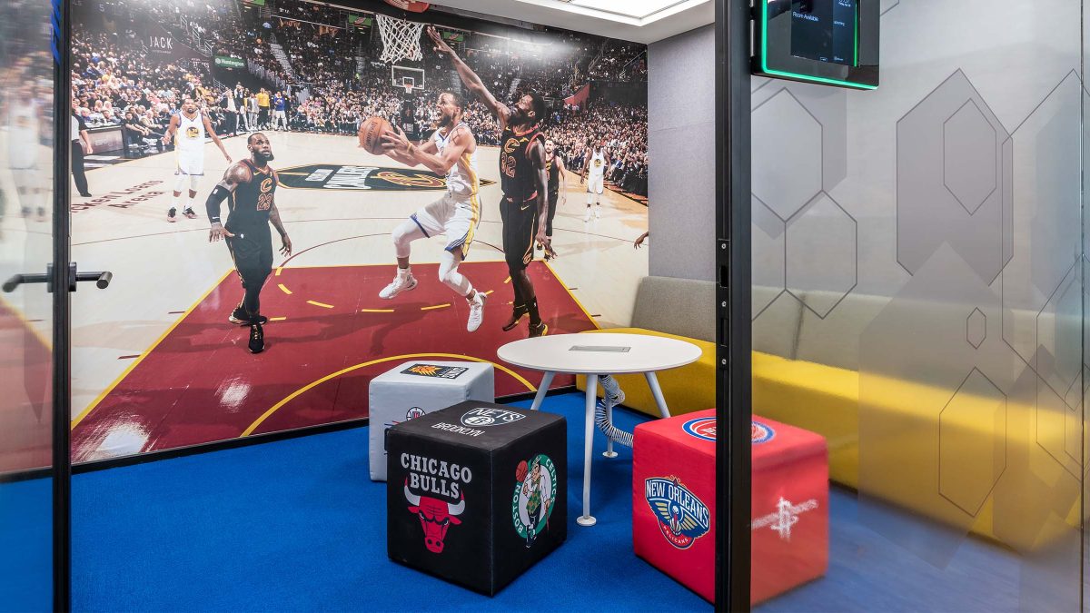 Colourful meeting room area filled with NBA merchandise and large artwork of basketball game.