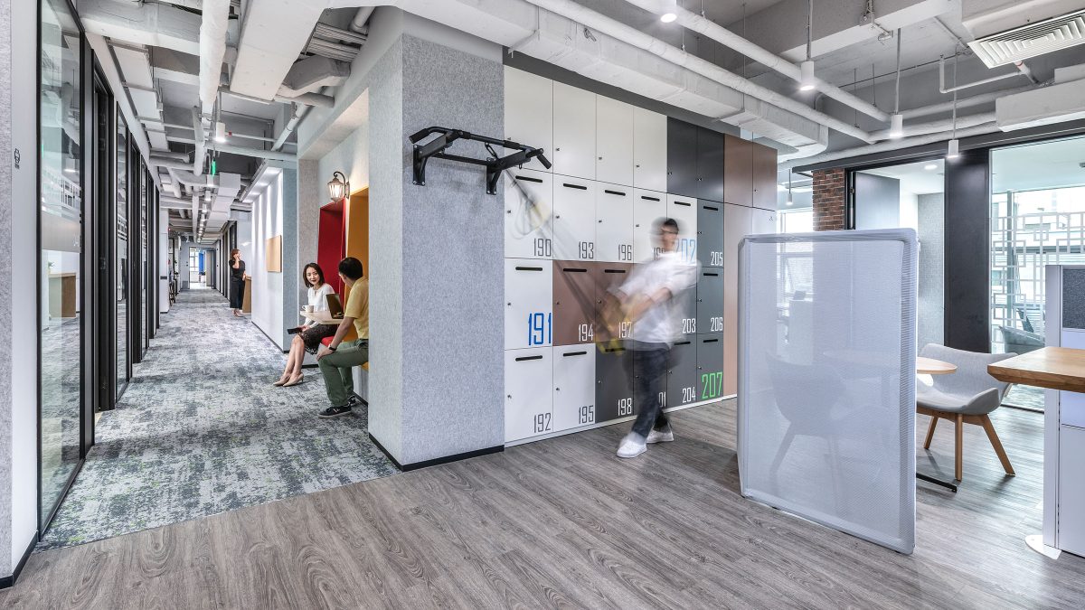 man walking down corridor and people collaborating in booths