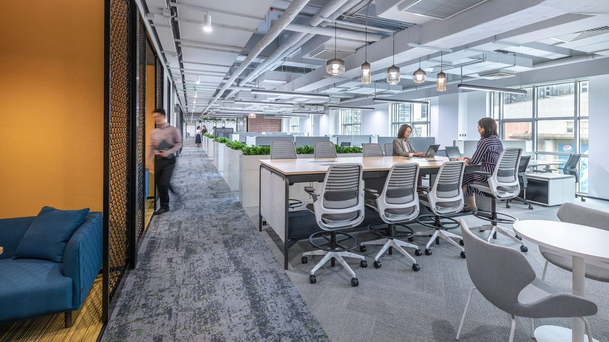 Woman working at open plan office and person in corridor