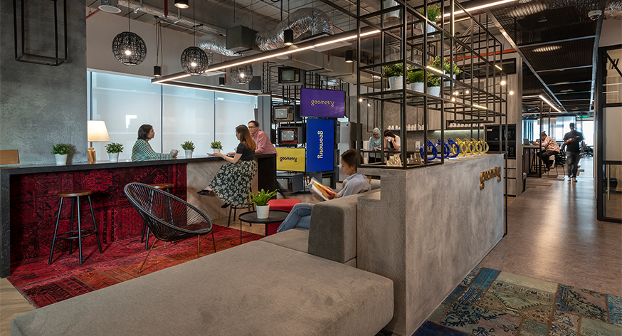 people talking in casual seating area by counter and woman sitting and reading