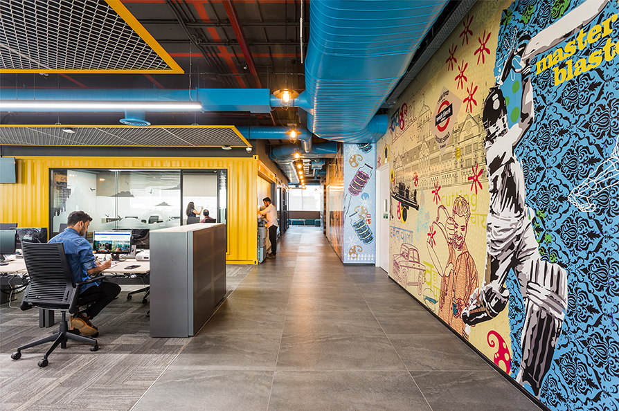 man at desk, people in corridor and view of art mural