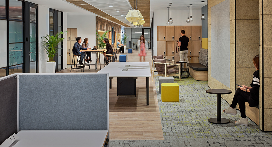 people collaborating in breakout area, man by lockers and woman in corridor