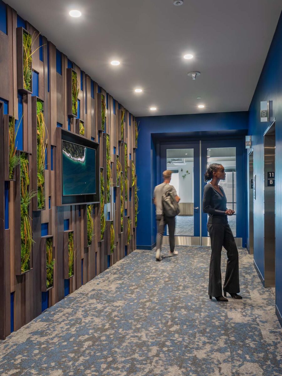 woman waiting for lift and man walking through corridor