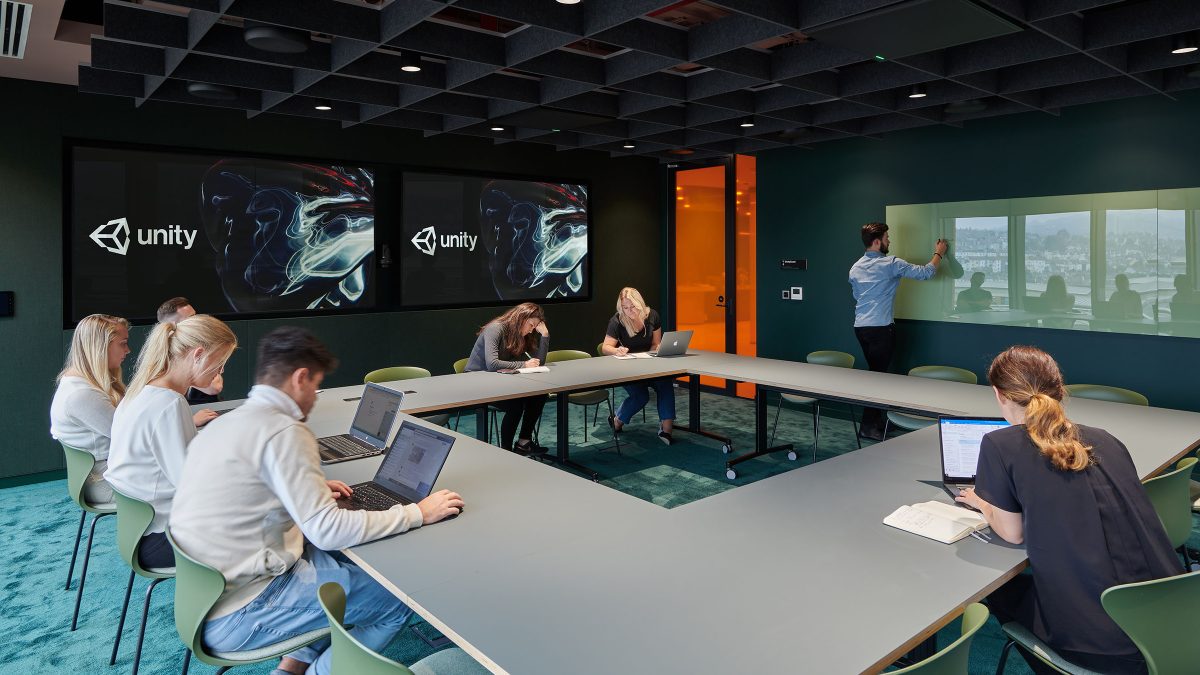 people collaborating in meeting room with man giving presentation