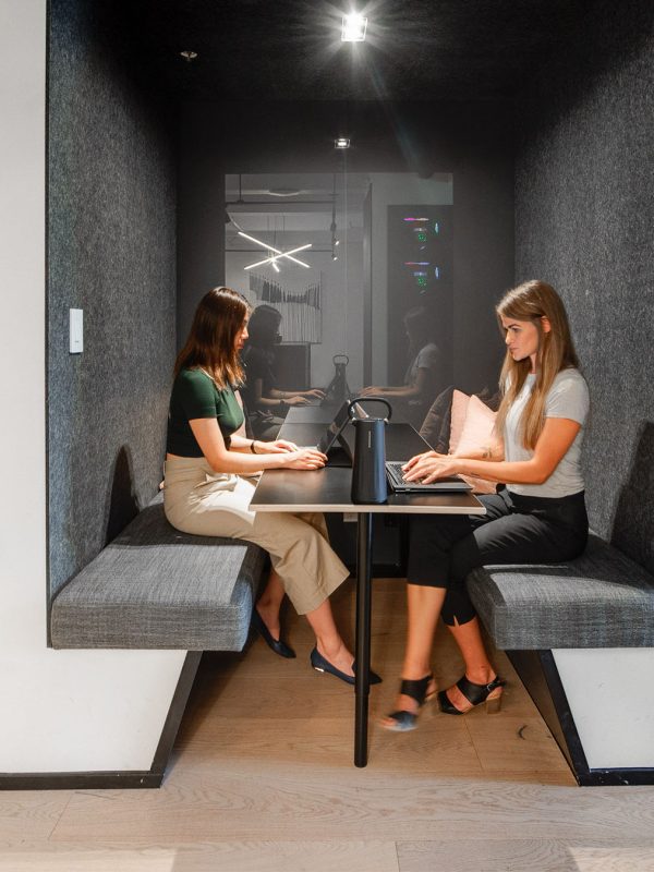 people collaborating in meeting room and woman on phone outside of meeting room