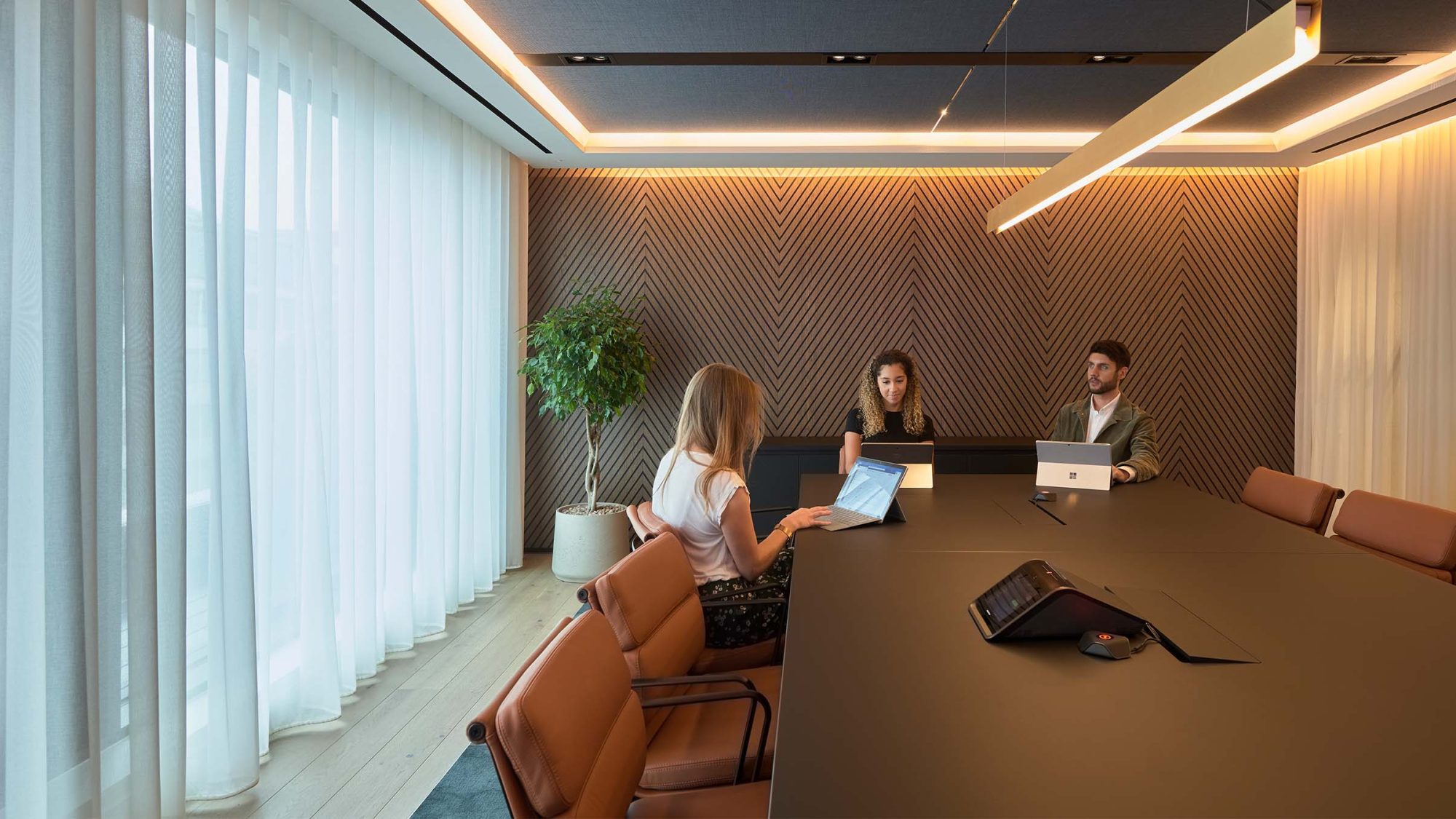 Employees sitting at a long table in a boardroom.