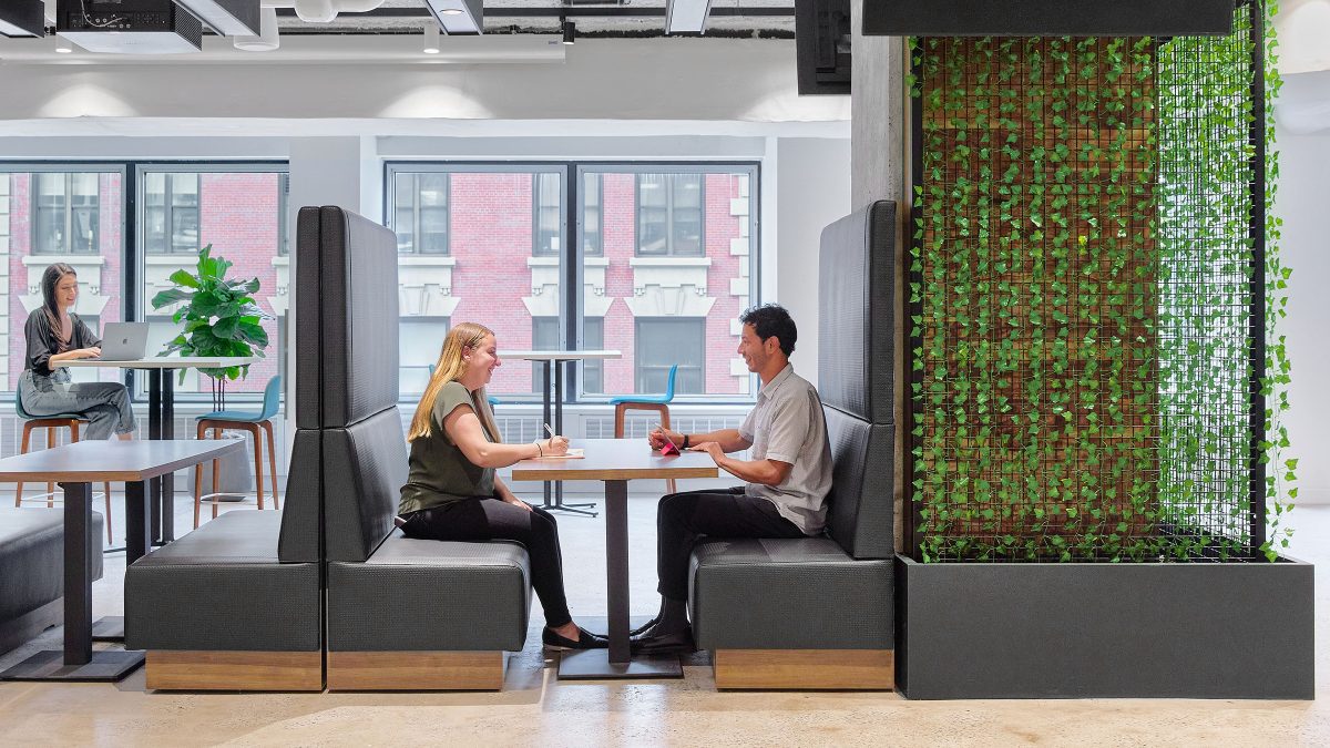 people collaborating in booth and woman at table