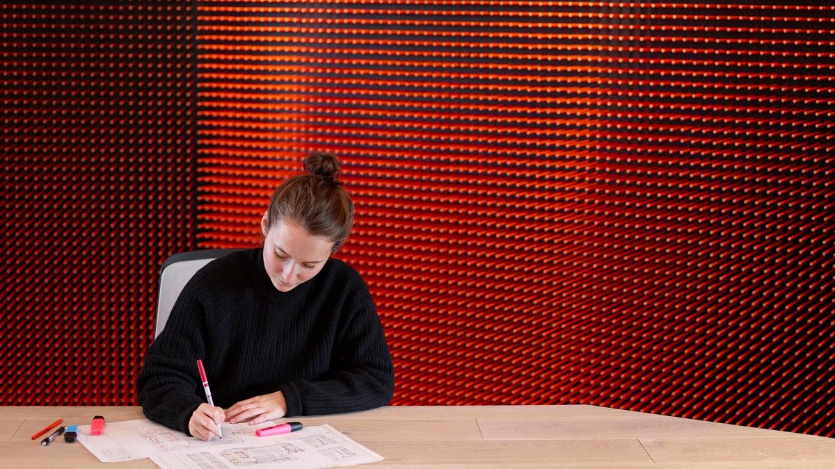 woman sitting in london office in front of orange pencil wall