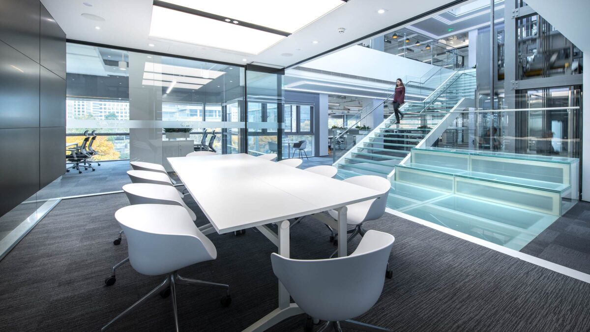 woman walking down staircase into space with desk and chairs