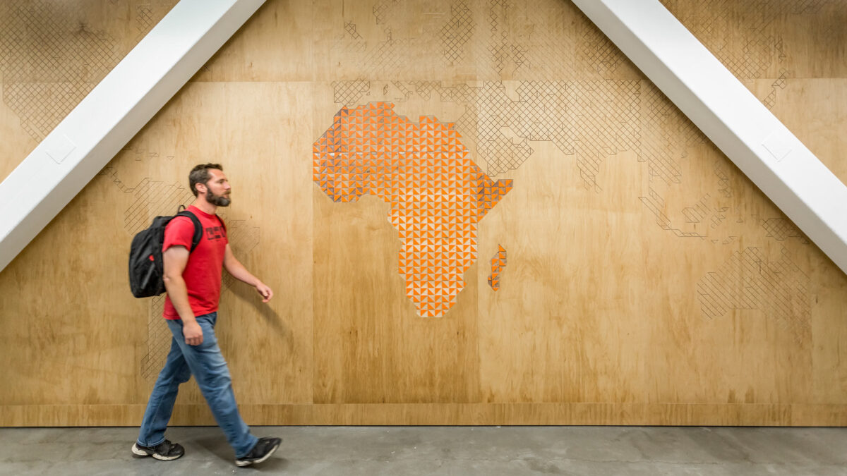 man walking past graphic map on wall