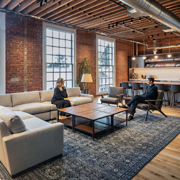 people in lounge and woman in kitchen