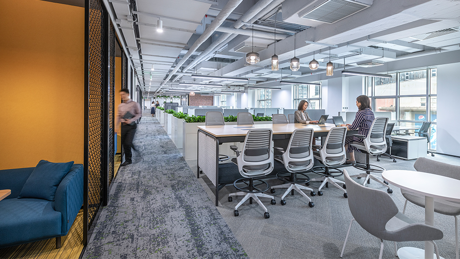 women working at desks, man walking into booth