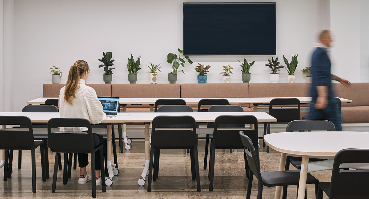 woman working at table while man walks