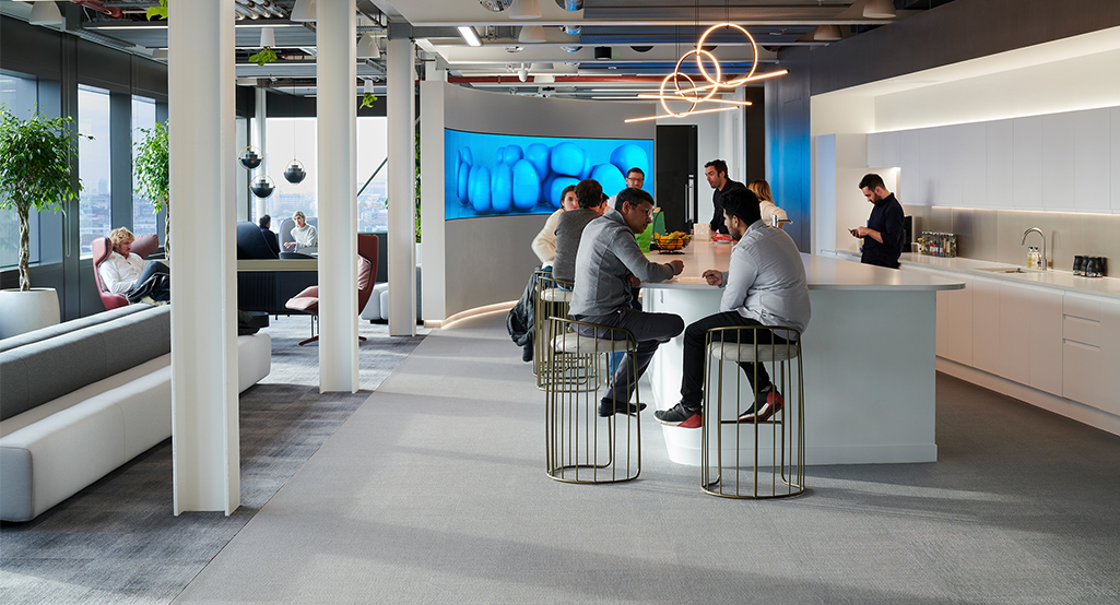 people in kitchen and man sitting in casual seating area