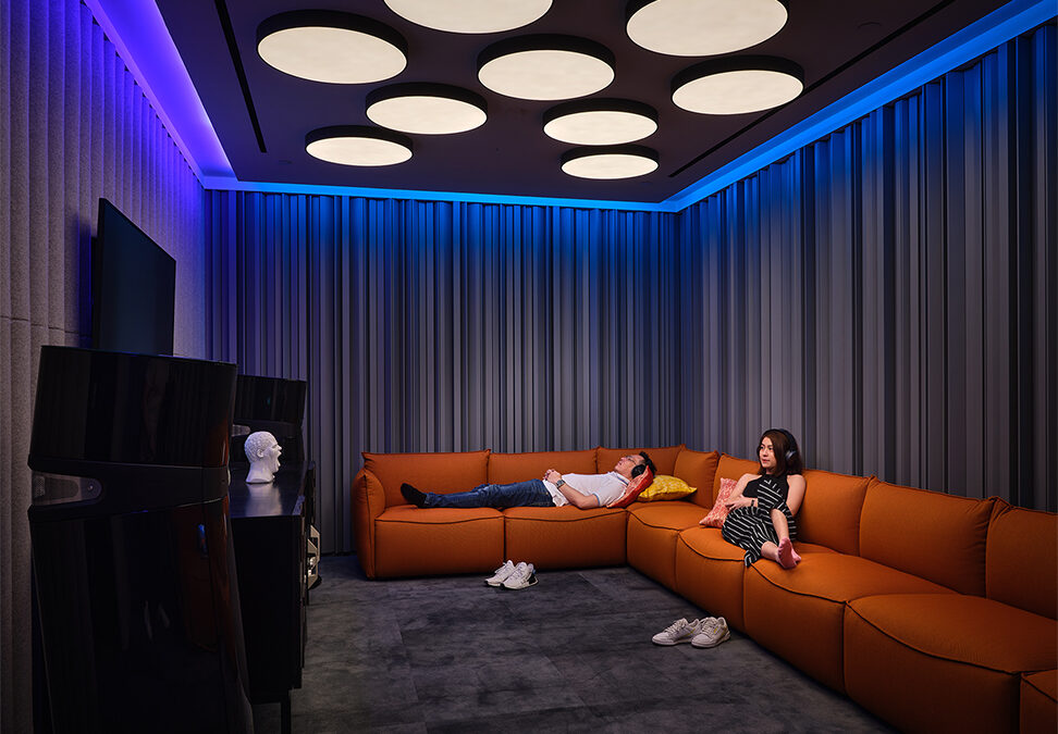 Man sleeping on chair while woman sits upright and watches screen