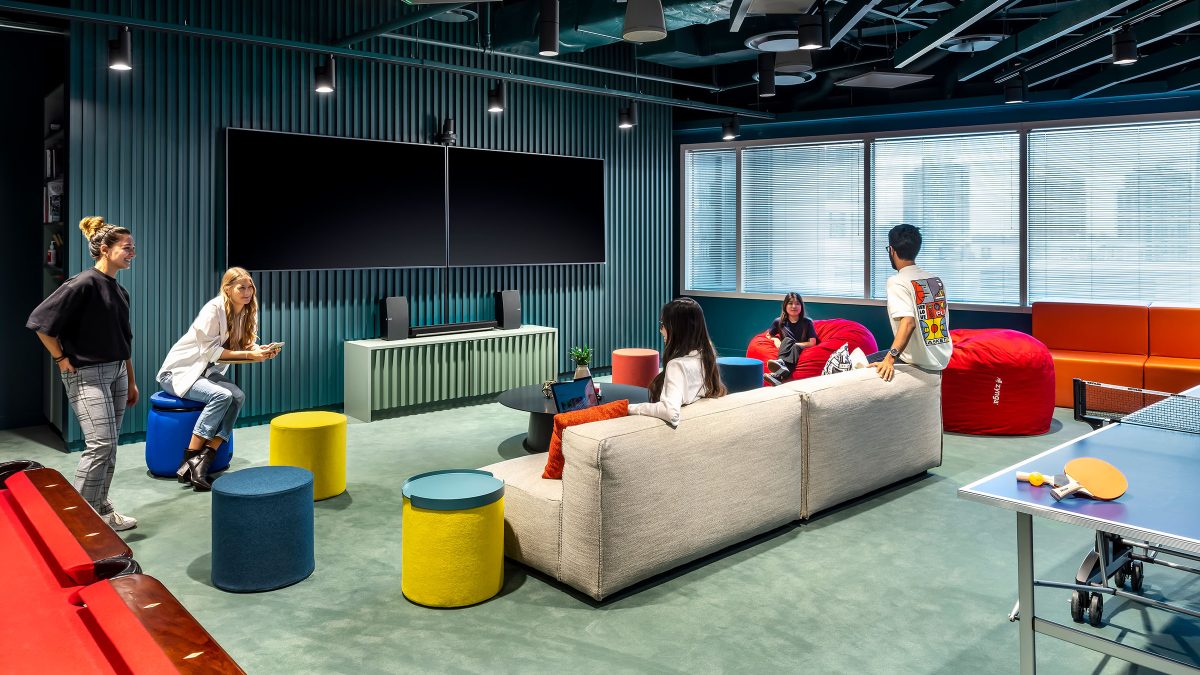 Open meeting area design at Zynga in Toronto features flexible and moveable furniture, comfortable seating and large tv screens for remote dial-in for hybrid employees.