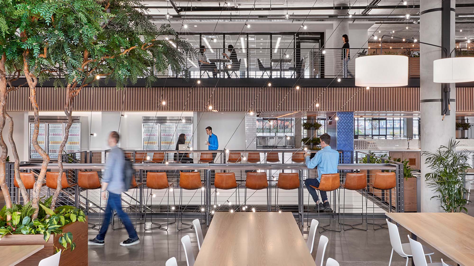 Workplace interior design for a corporate headquarters promotes community and employee experience with a large open dining experience.