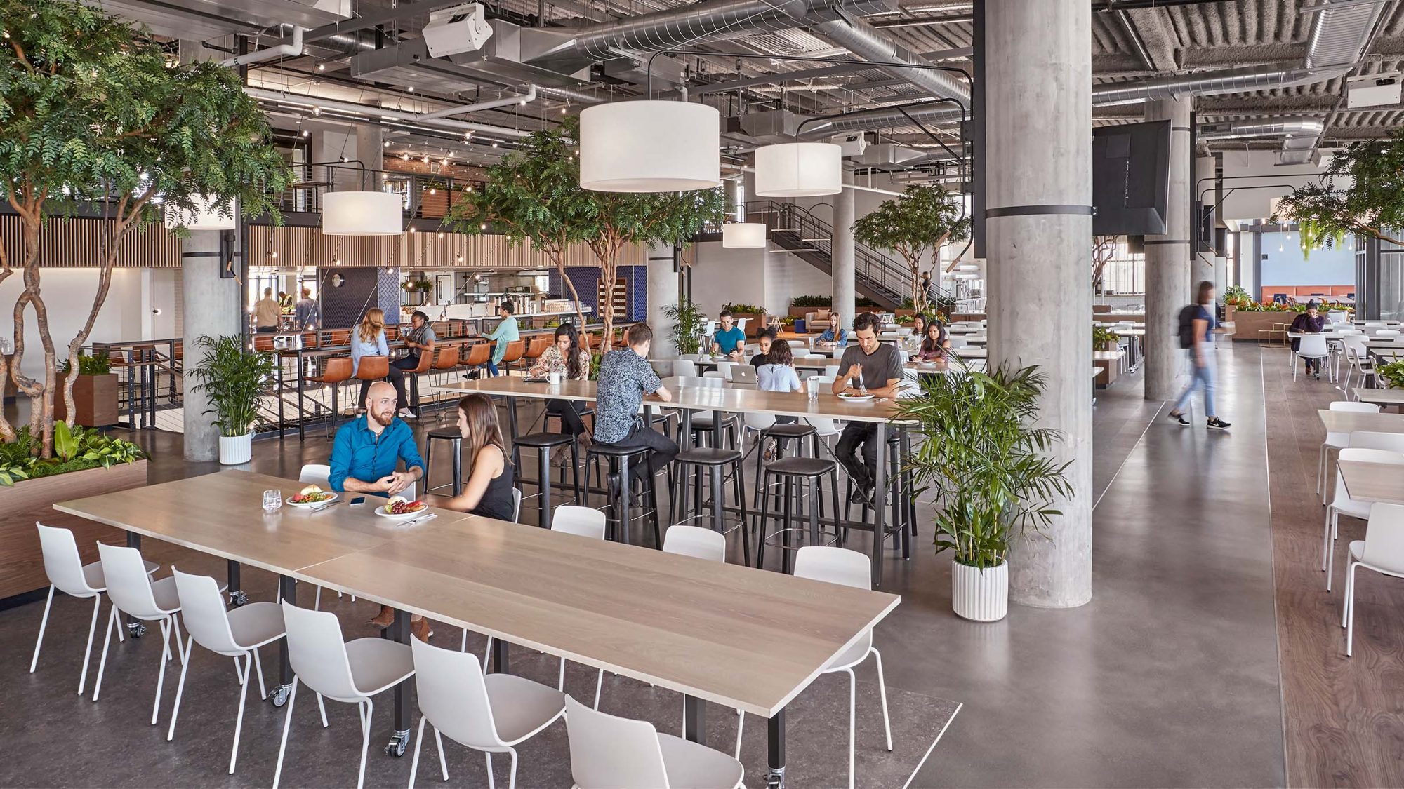 M Moser’s interior office design for a San Francisco client features a large servery-style kitchen with large communal tables.