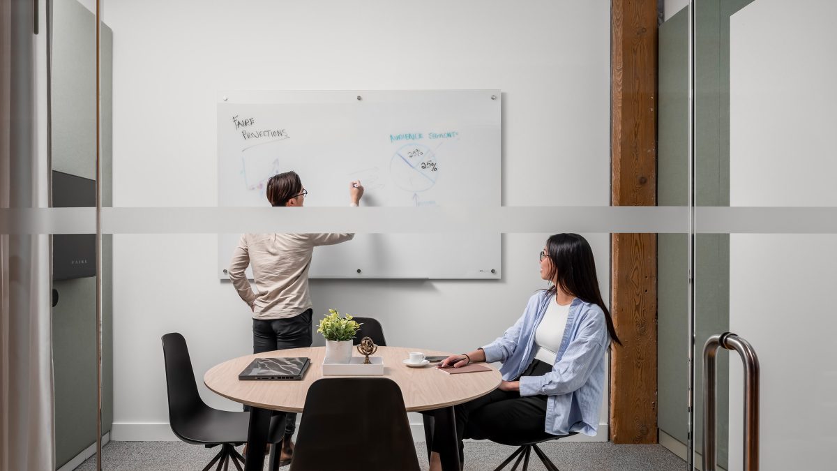 Corporate office meeting room design by M Moser featuring whiteboard for team collaboration and planning.