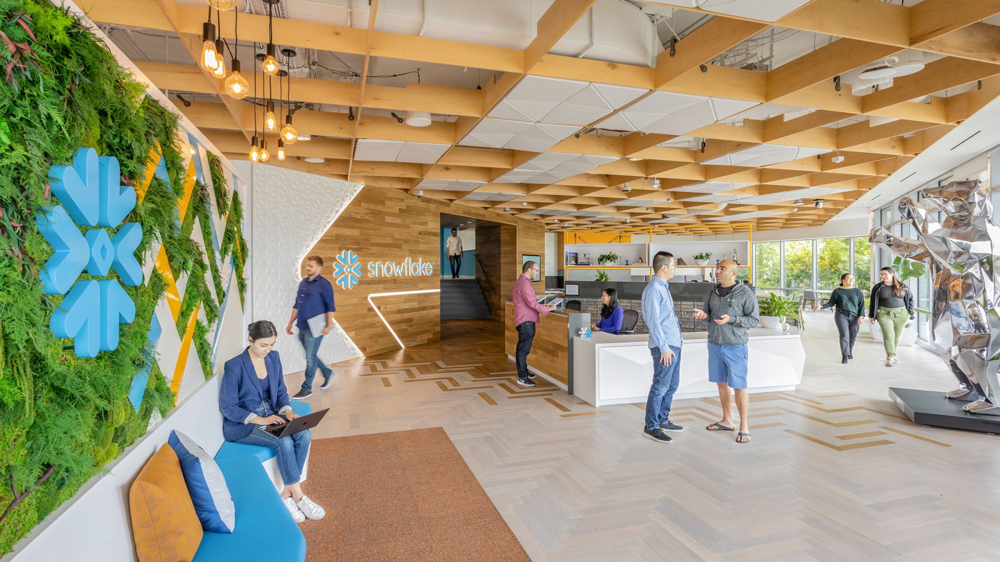 The main entrance lobby to Snowflake’s global headquarters features custom logo signage, a green wall, integrated lighting and materials that evoke a snowy mountain design.
