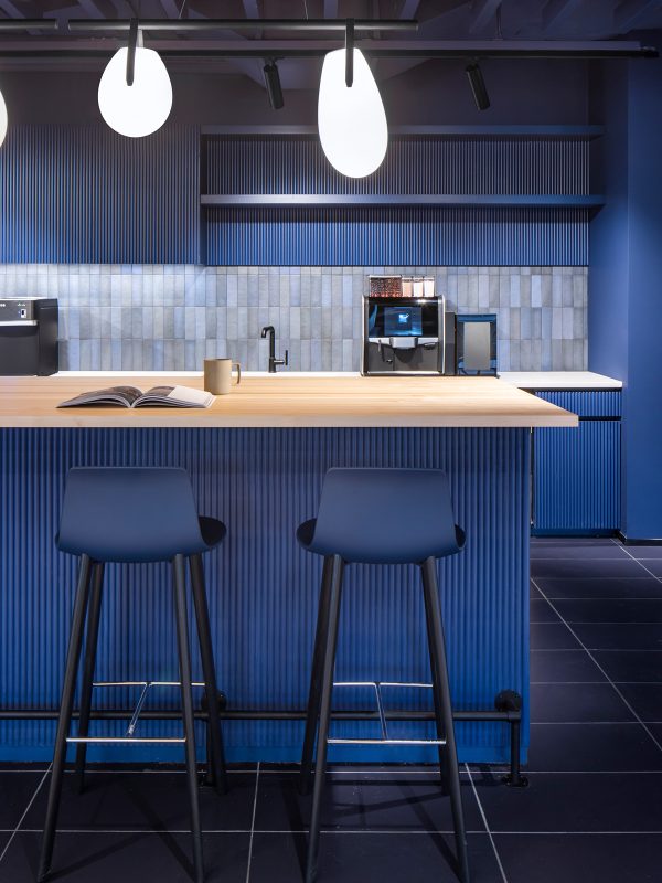 Kitchen interior design in brand colours featuring a wooden countertop and comfortable seating for employees to enjoy their lunch at.