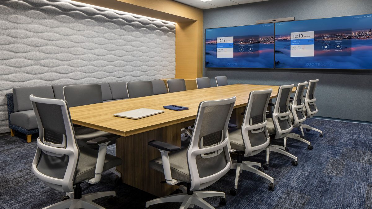 Meeting room design by M Moser featuring a long boardroom table, technology to support remote workers and acoustic interventions for privacy and sound absorption.
