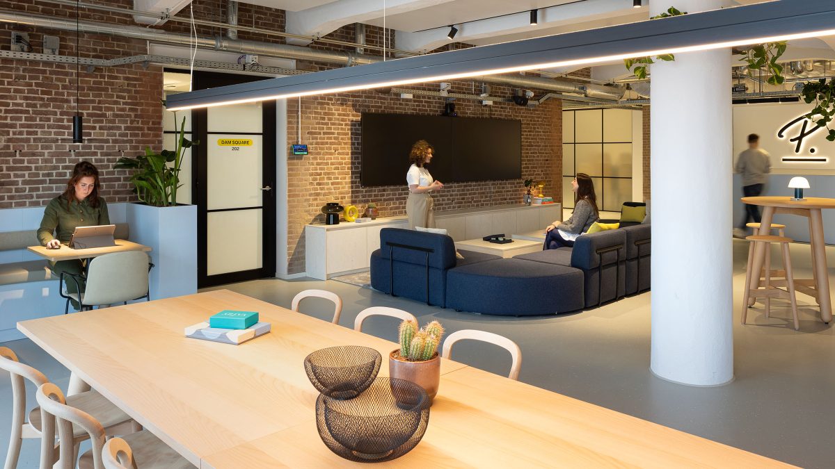 Communal lounge in reception of office space with exposed brick walls.