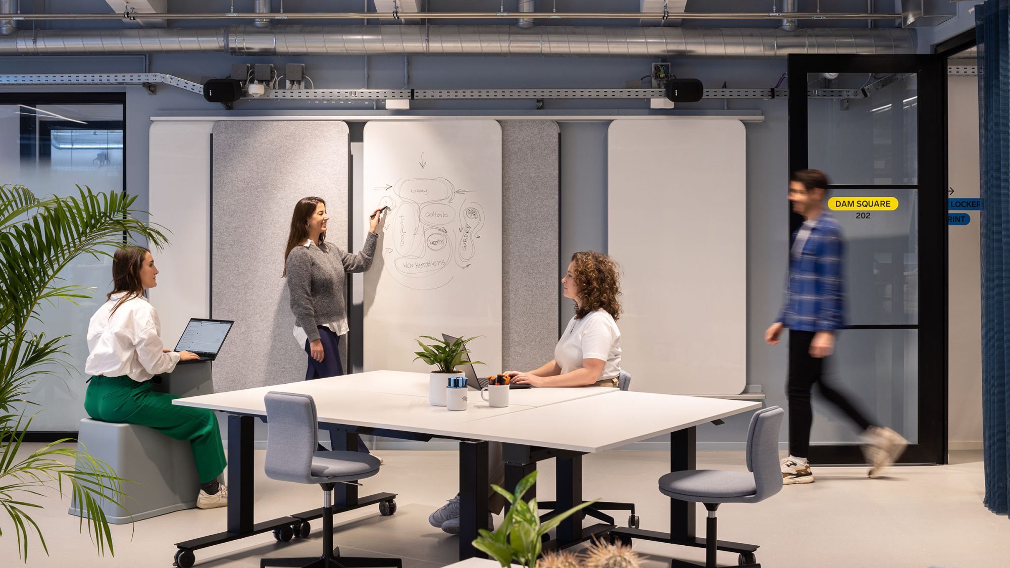Interior design that supports the work day featuring modular whiteboards, tables and chairs.