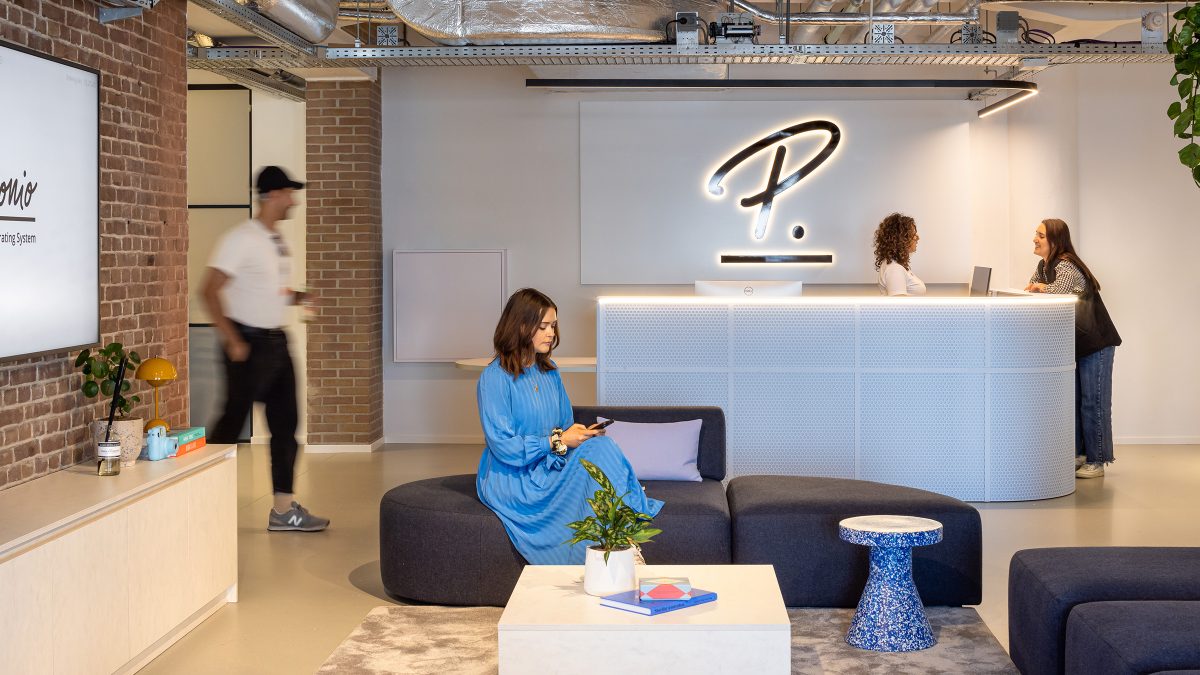 Office interior reception space with woman sitting in lounge 