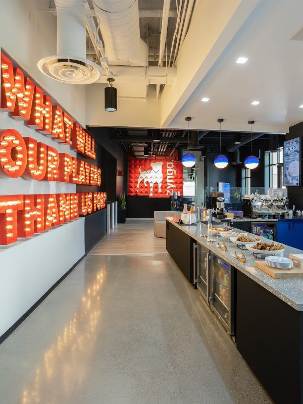 Corporate kitchen interior design featuring buffet style set up, branded graphics, neon lights and Zynga logo.
