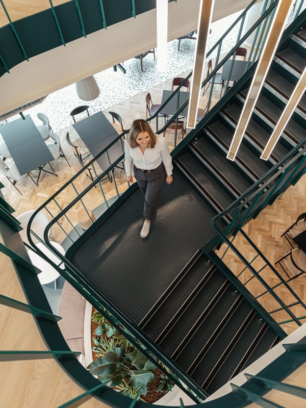 a person walking down a staircase with pendant lighting