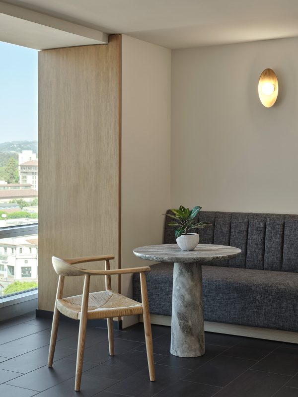 High-end interior design by M Moser in Los Angeles featuring a marble plinth table, solid wood chair and banquet sofa for private meetings or individual work.