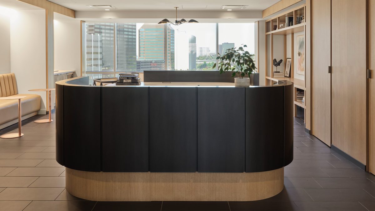 Welcoming reception area design by M Moser featuring a curved desk design made from natural wood.