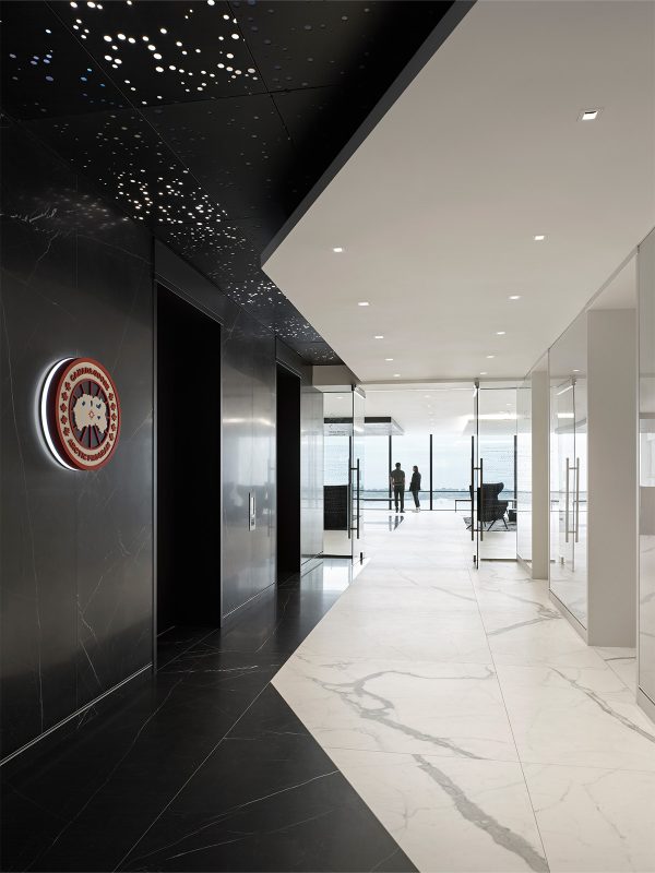 Corporate office interior design by M Moser featuring client logo and high-end materials in an elevator corridor. 