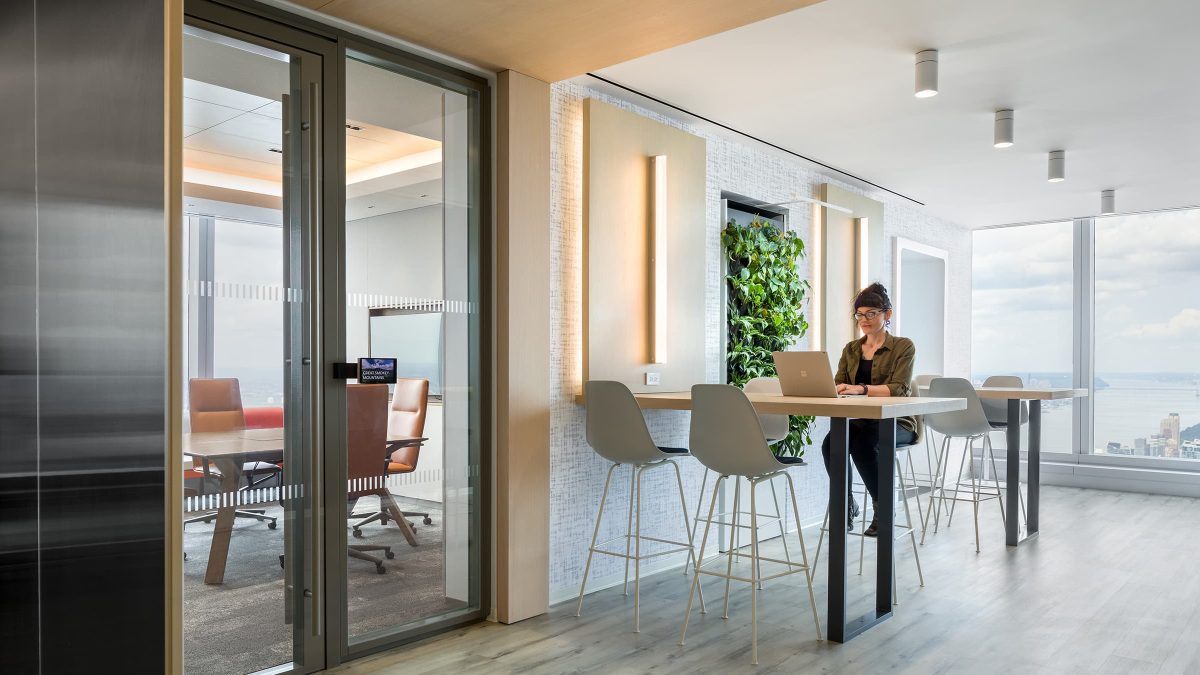 DNB New York woman at table and view of meeting room and green wall