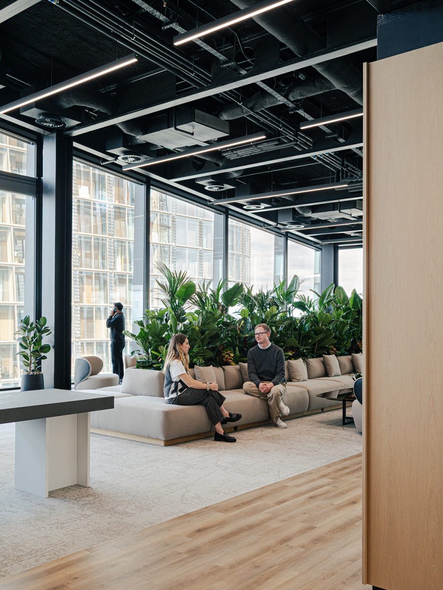 two-people-sat-in-double-height-lobby-space-at-wipro-london-office